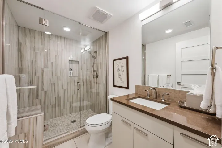 Glass-enclosed shower with vertical tile work and a built-in niche
