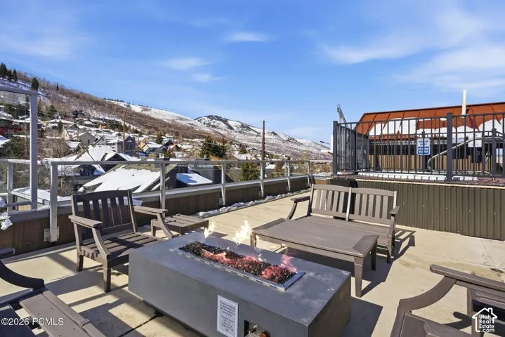 Rooftop patio featuring a built-in fire pit, a hot tub with metal railing, and glass panel railings