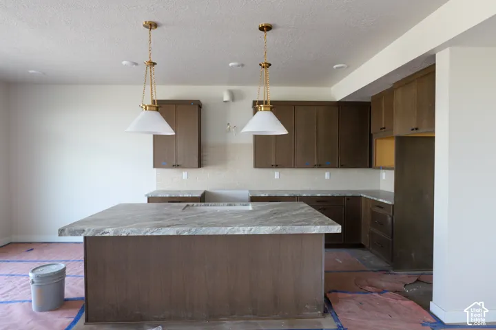 Kitchen featuring warm wood-finish cabinetry, light-toned stone countertops, and a full-height tile backsplash