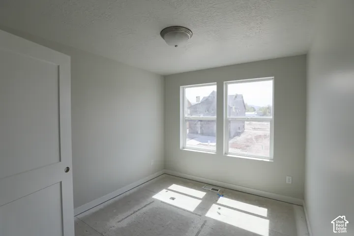 Room featuring neutral painted walls, two windows, a white interior door, and a flush mount ceiling light
