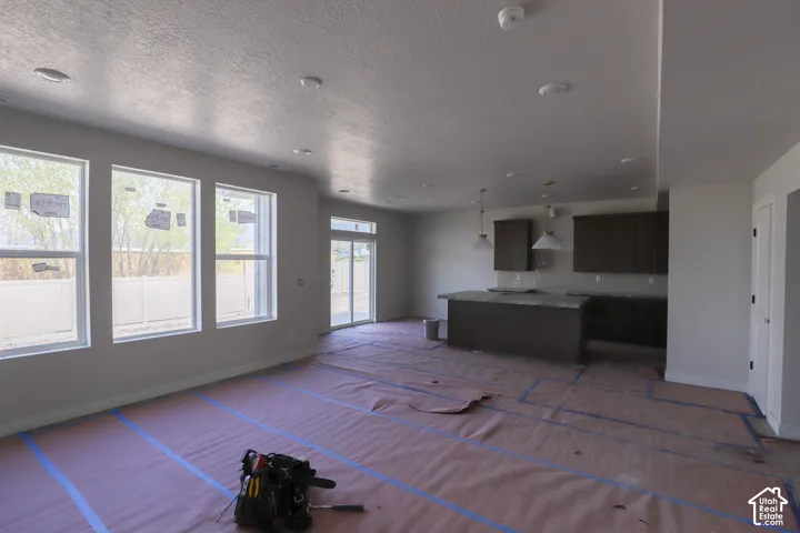 Open-concept living area with three large windows and a sliding glass door
