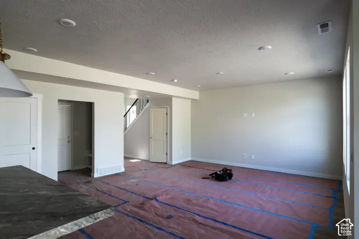 Recessed ceiling lighting, granite-finish countertop, white paneled doors, staircase with black handrail