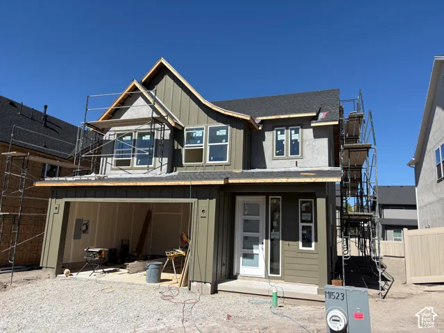 Two-story residence featuring a dark gray shingle roof, mixed-material siding, and multiple windows