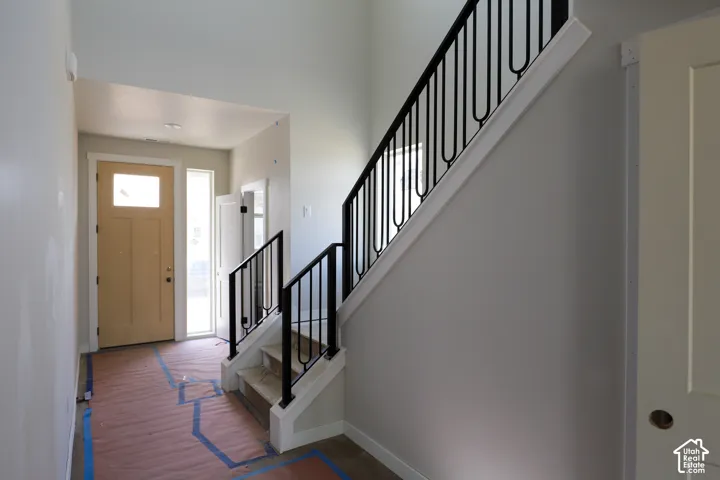 Entryway featuring a wood-panel door with transom window, side light, and a staircase with wrought iron balusters