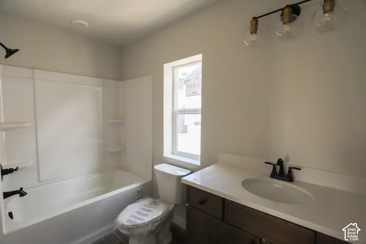 Bathroom featuring a white tub, dark bronze fixtures, a vanity with a white countertop, and a window