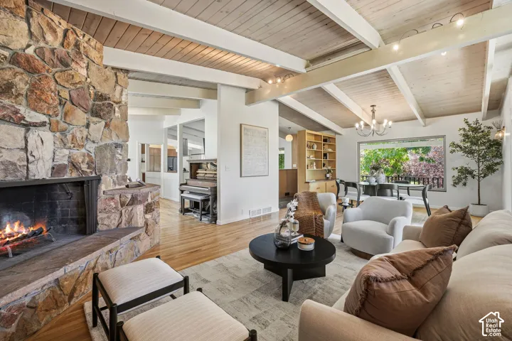 Wood-finish flooring, stone-clad fireplace, exposed beam ceiling, and built-in shelving