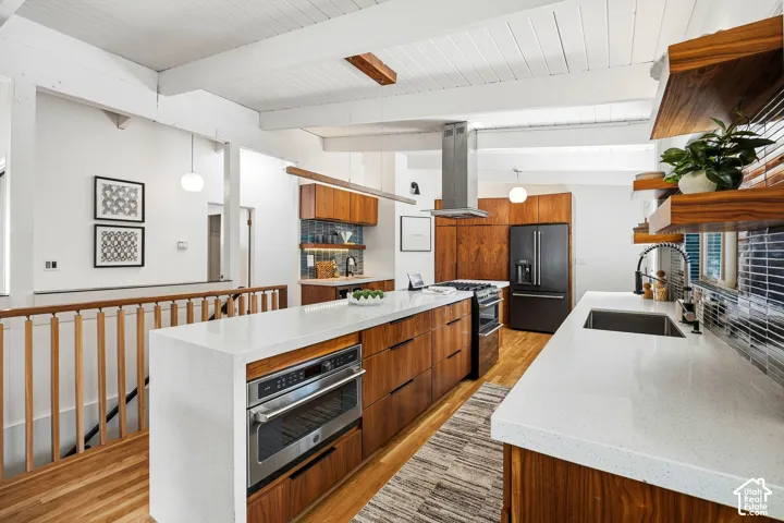 Kitchen featuring wood-finish cabinetry, white countertops, built-in stainless steel appliances, and a tile backsplash