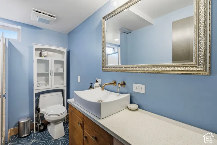 Modern vessel sink with wall-mounted faucet, wood-finish vanity, and a light-toned countertop