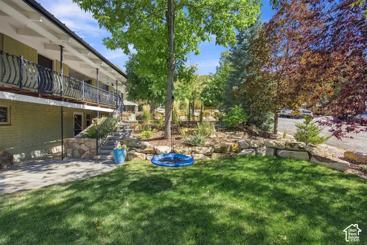 Expansive green lawn with mature trees and a multi-level stone retaining wall