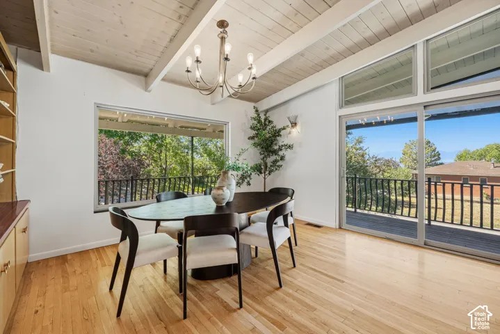 Vaulted wood-paneled ceiling, light wood-finish flooring, built-in cabinetry, large window, and sliding glass doors to outdoor deck