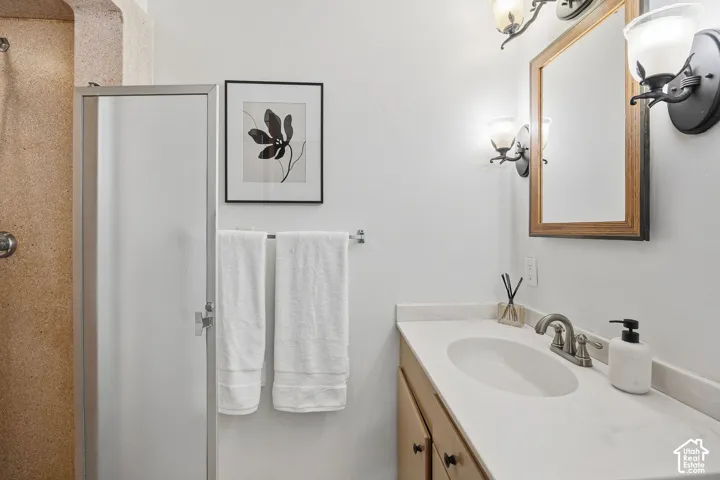 Bathroom featuring a single vanity with an integrated sink, polished chrome faucet, and a framed mirror