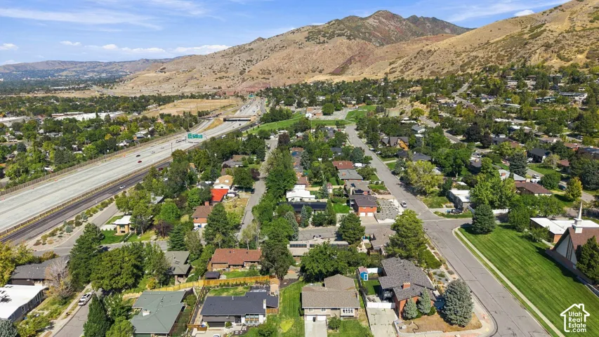 Mountain-backed suburban landscape with established residential areas, a prominent highway, and mature tree-lined streets