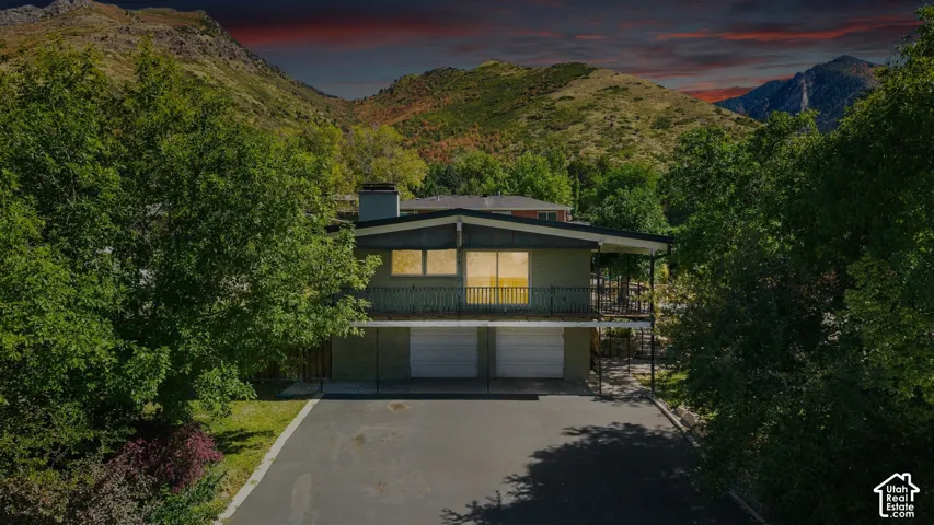 Multi-level exterior with a prominent balcony, dual garage doors, and a paved driveway