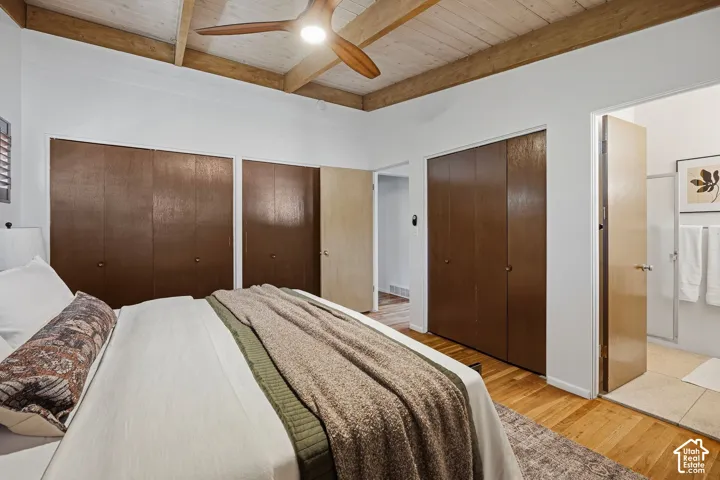 Vaulted ceiling with exposed wood beams, ceiling fan, wood-finish flooring, built-in bi-fold closets, and a built-in recessed light fixture