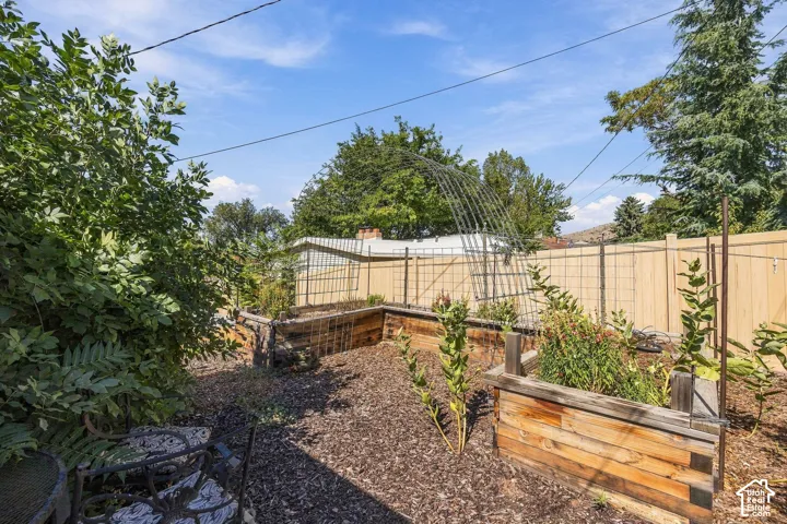 Backyard featuring multiple raised garden beds, wood chip ground cover, and a privacy fence