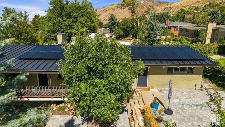 Metal roof with integrated solar panels, exterior siding, and a stone paver patio