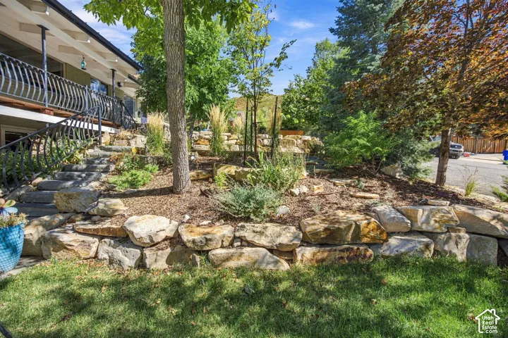 Tiered landscaping featuring natural rock retaining walls, mature trees, and varied plantings