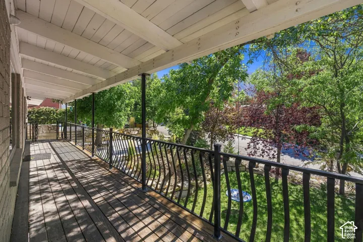 Covered porch featuring wood-finish flooring and black wrought iron railing