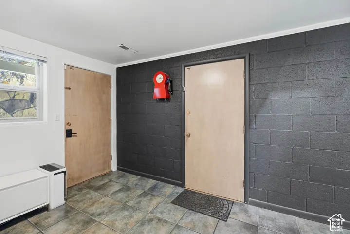 Tiled flooring, painted cinder block wall, interior door, window with horizontal blinds