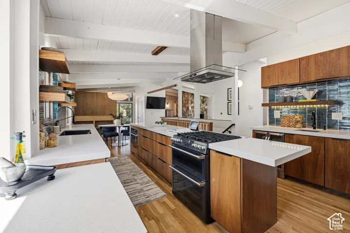 Kitchen featuring wood-finish cabinetry, white countertops, tile backsplash, wood-finish flooring, and a stainless steel range hood