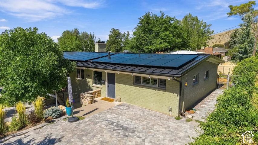 Brick exterior with a dark trim roofline, integrated solar panels, and a paver driveway