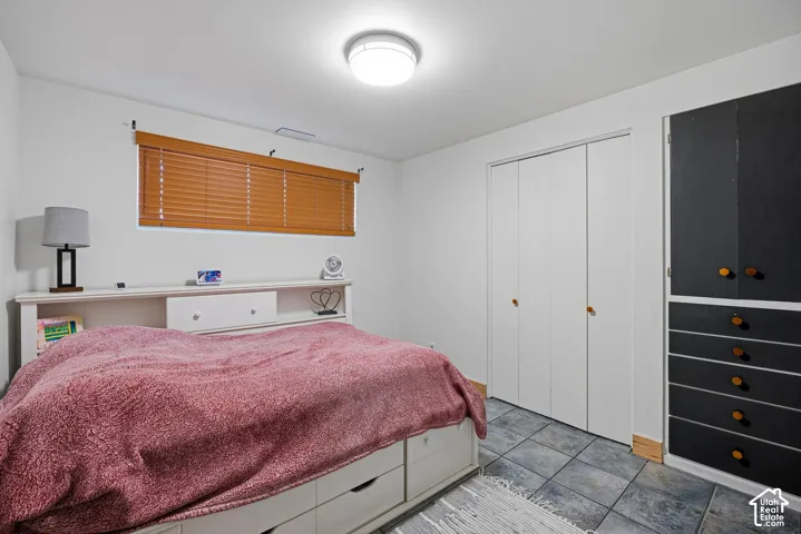 Bi-fold closet doors, built-in storage cabinet, ceramic tile flooring, wood-finish window blinds, recessed ceiling light fixture