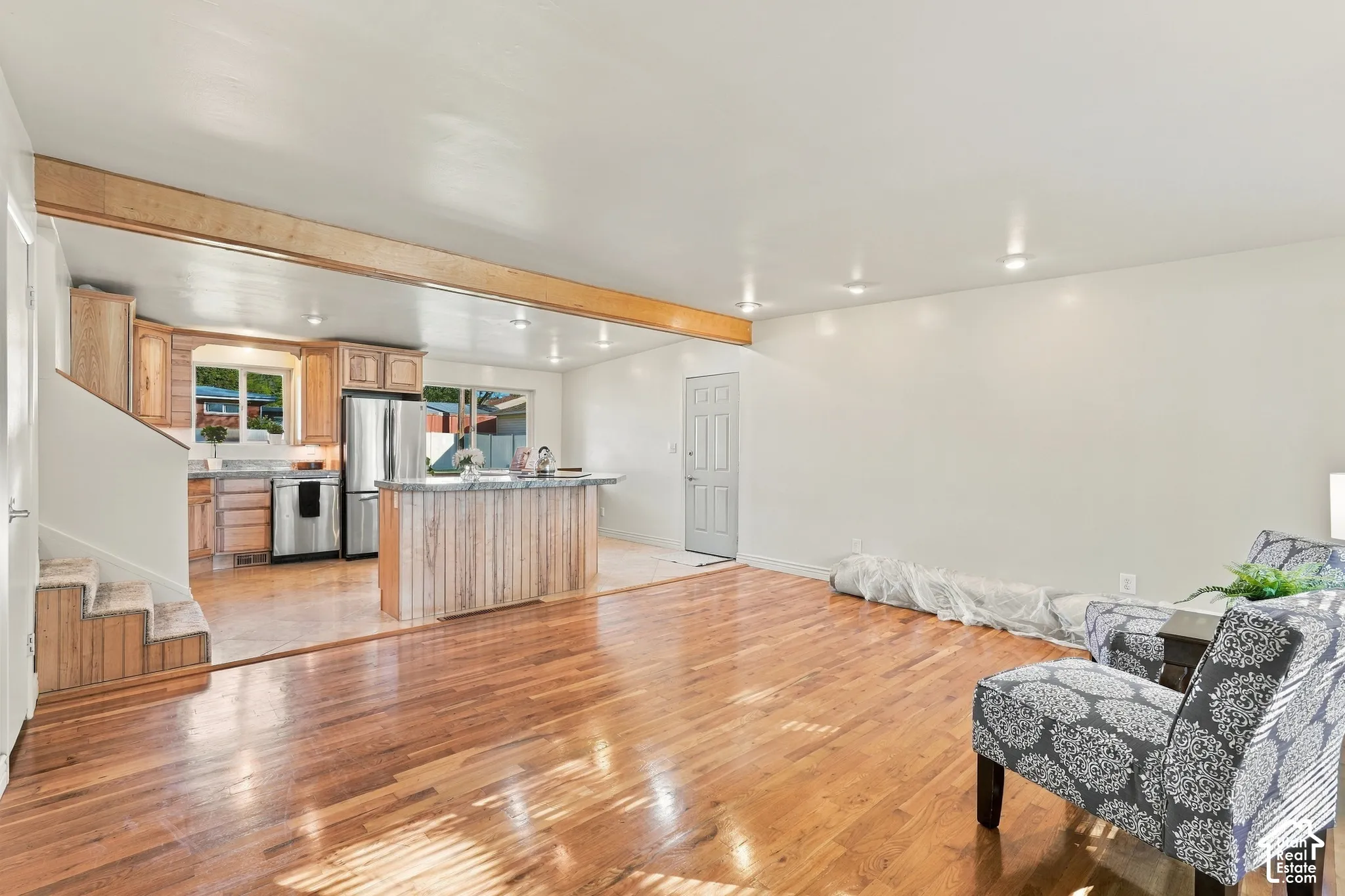 Wood-finish flooring throughout, recessed lighting, and a light wood-tone exposed beam