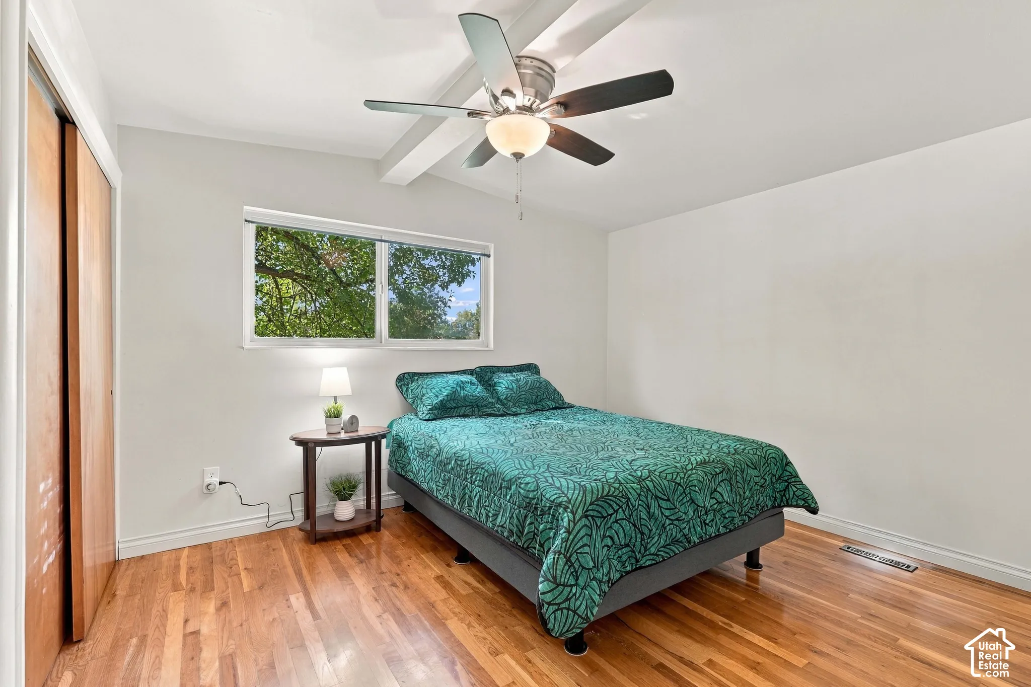 Hardwood flooring, white walls, and a window with natural light