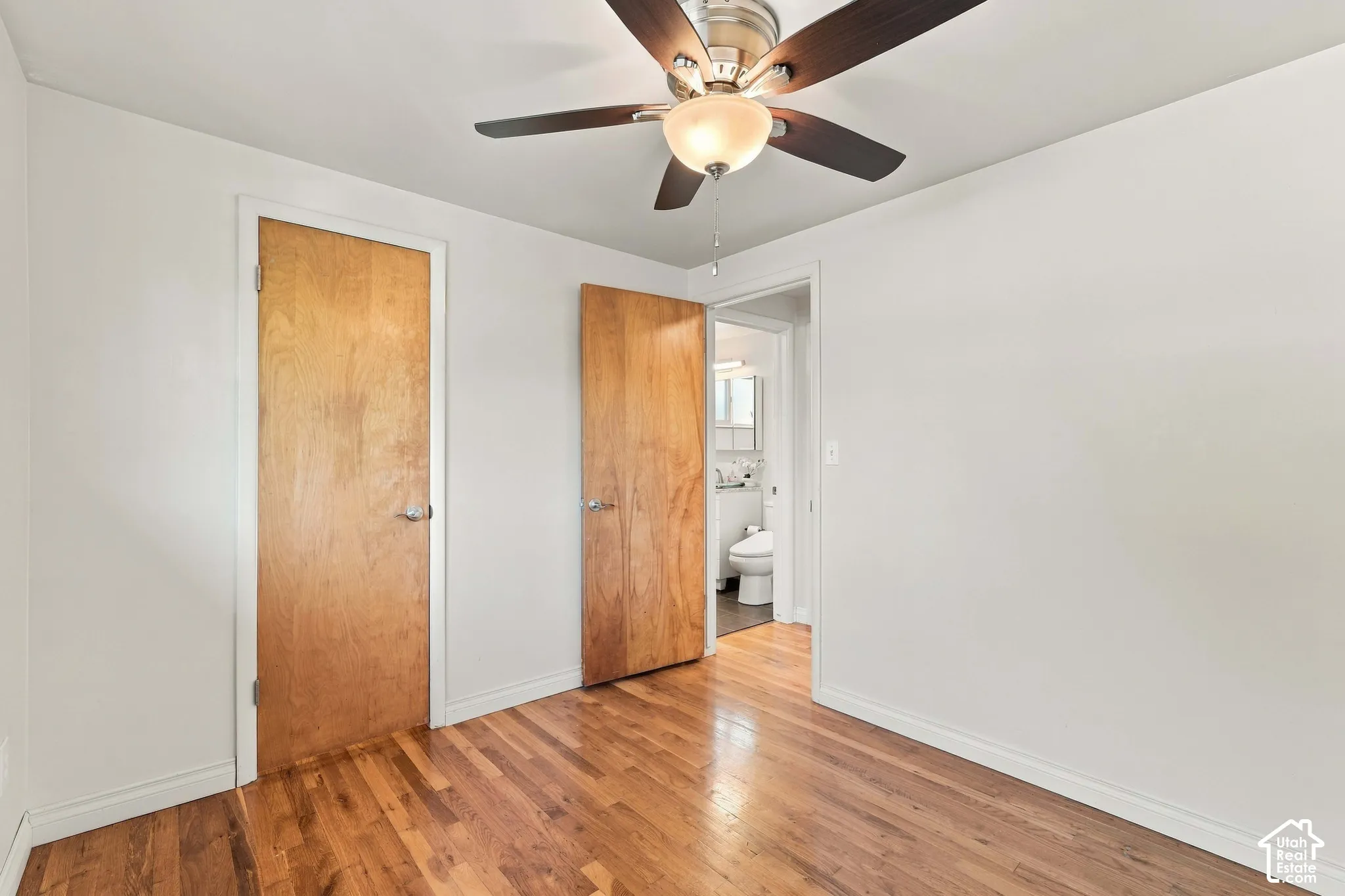 Hardwood flooring, ceiling fan with integrated lighting, wood-finish interior doors, and white walls