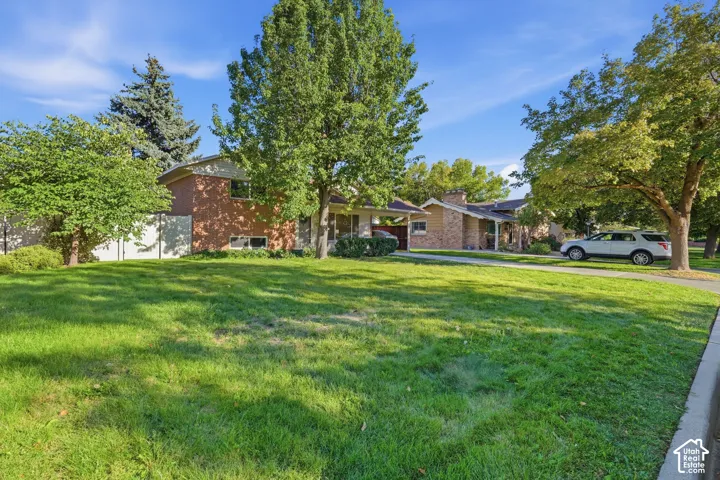 Brick exterior, mature trees, green lawn, paved driveway