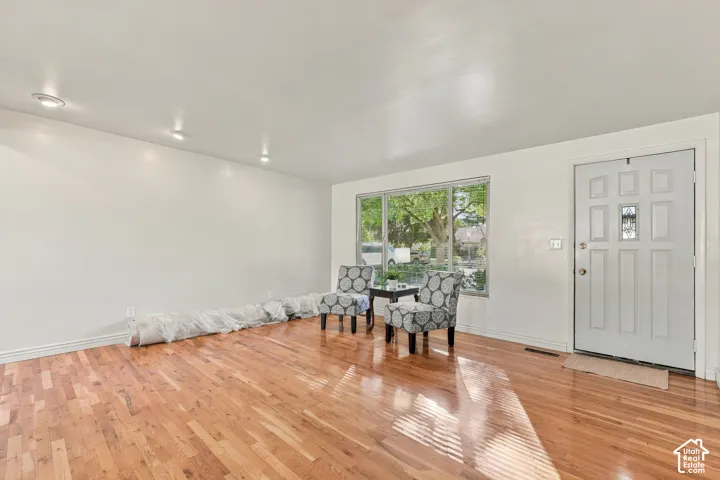 Hardwood flooring, recessed lighting, white paneled entry door with decorative glass insert, and large picture window