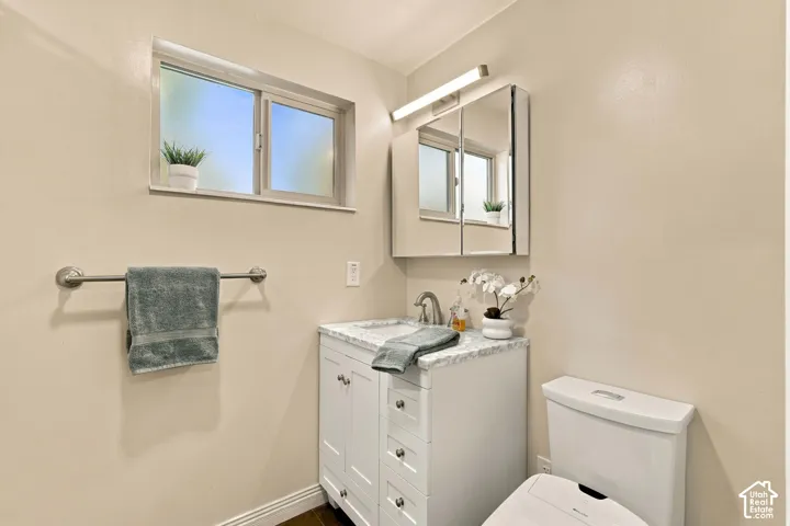 Bathroom featuring a white vanity with a marble-finish countertop, under-mount sink, and a mirrored medicine cabinet