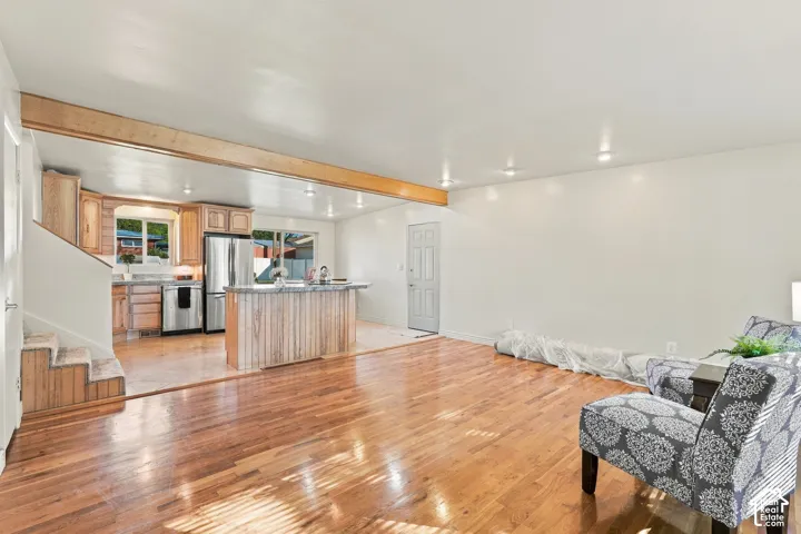 Wood-finish flooring throughout, recessed lighting, and a light wood-tone exposed beam