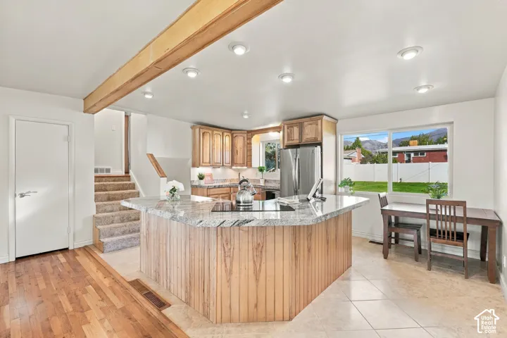 Kitchen featuring a large island with a granite countertop, wood cabinetry, stainless steel appliances, and recessed lighting