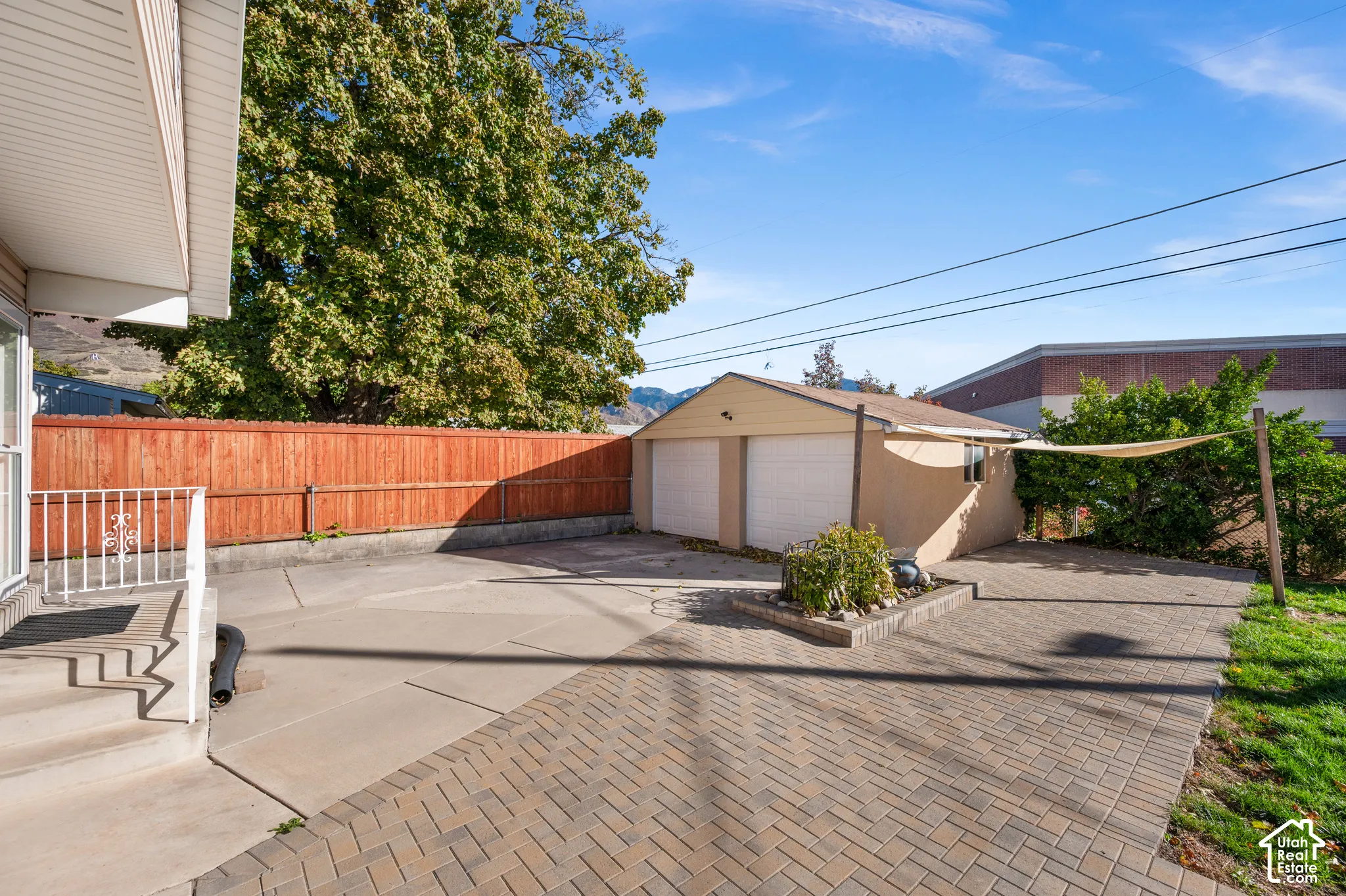 Outdoor area featuring a detached two-car garage, expansive herringbone-patterned paver patio, concrete slab, and wood privacy fencing