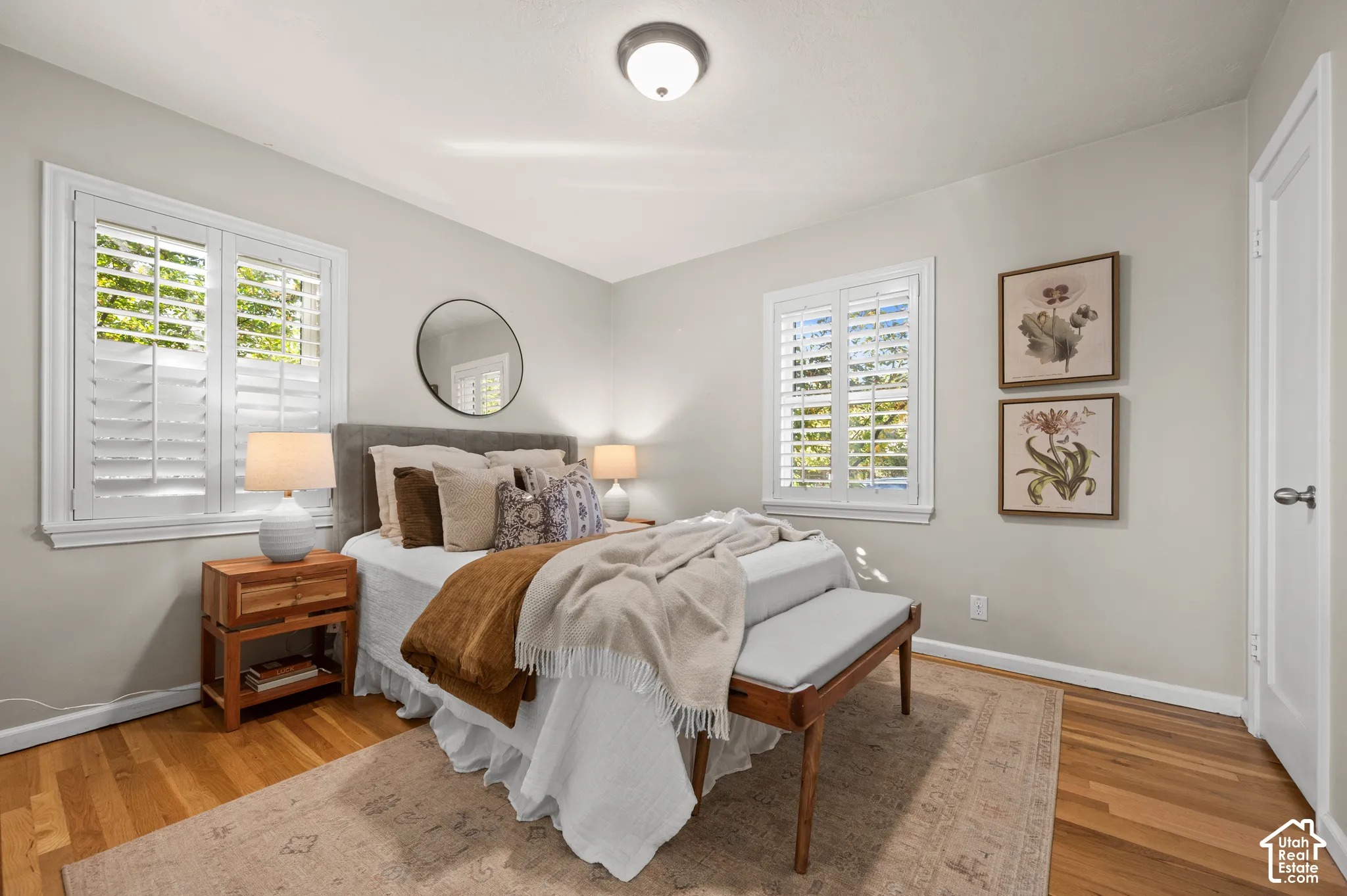 Wood-finish flooring, dual windows with white plantation shutters, and a central ceiling light fixture