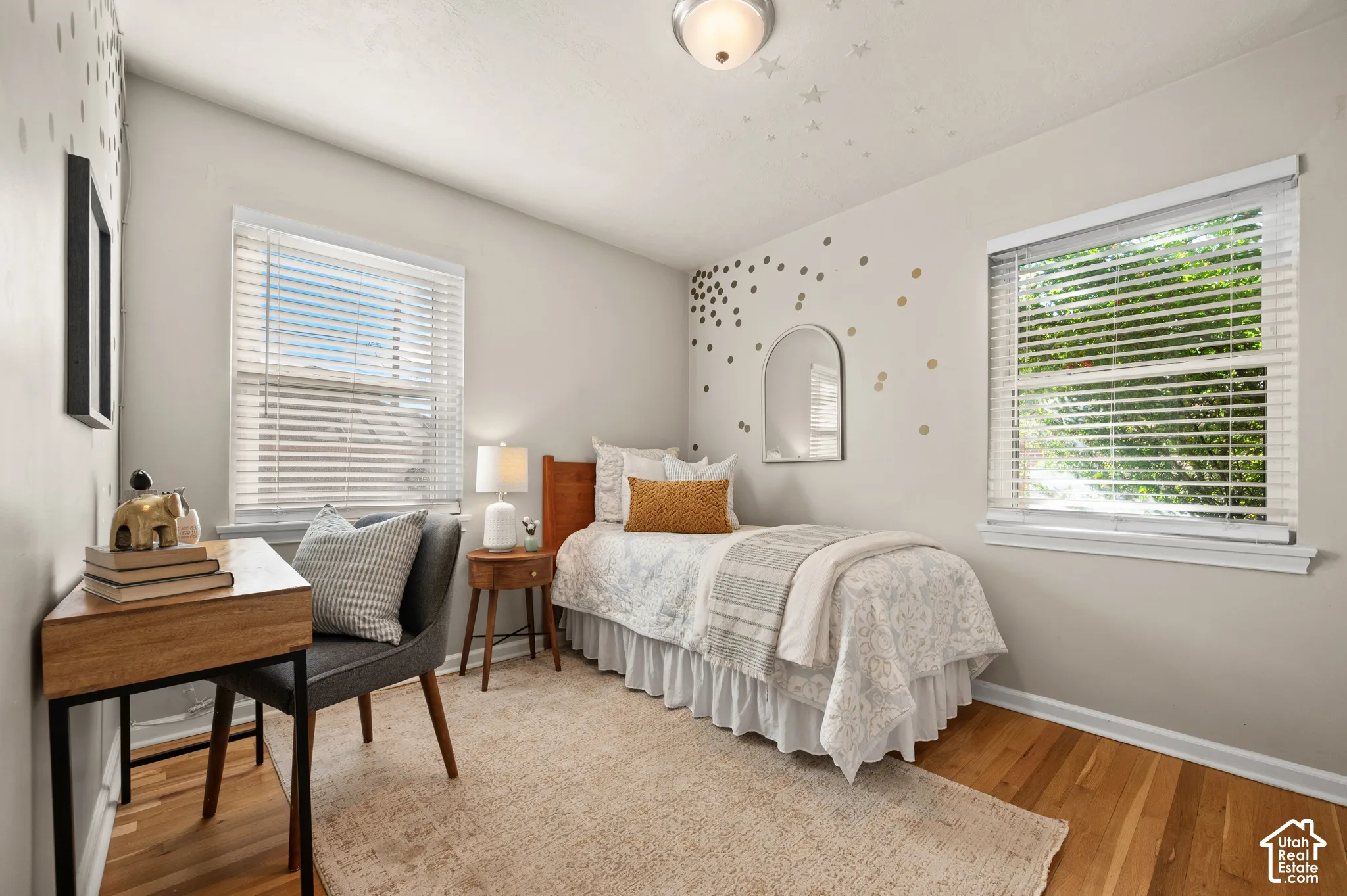 Room featuring wood-finish flooring, two windows with horizontal blinds, and a flush-mount ceiling light fixture