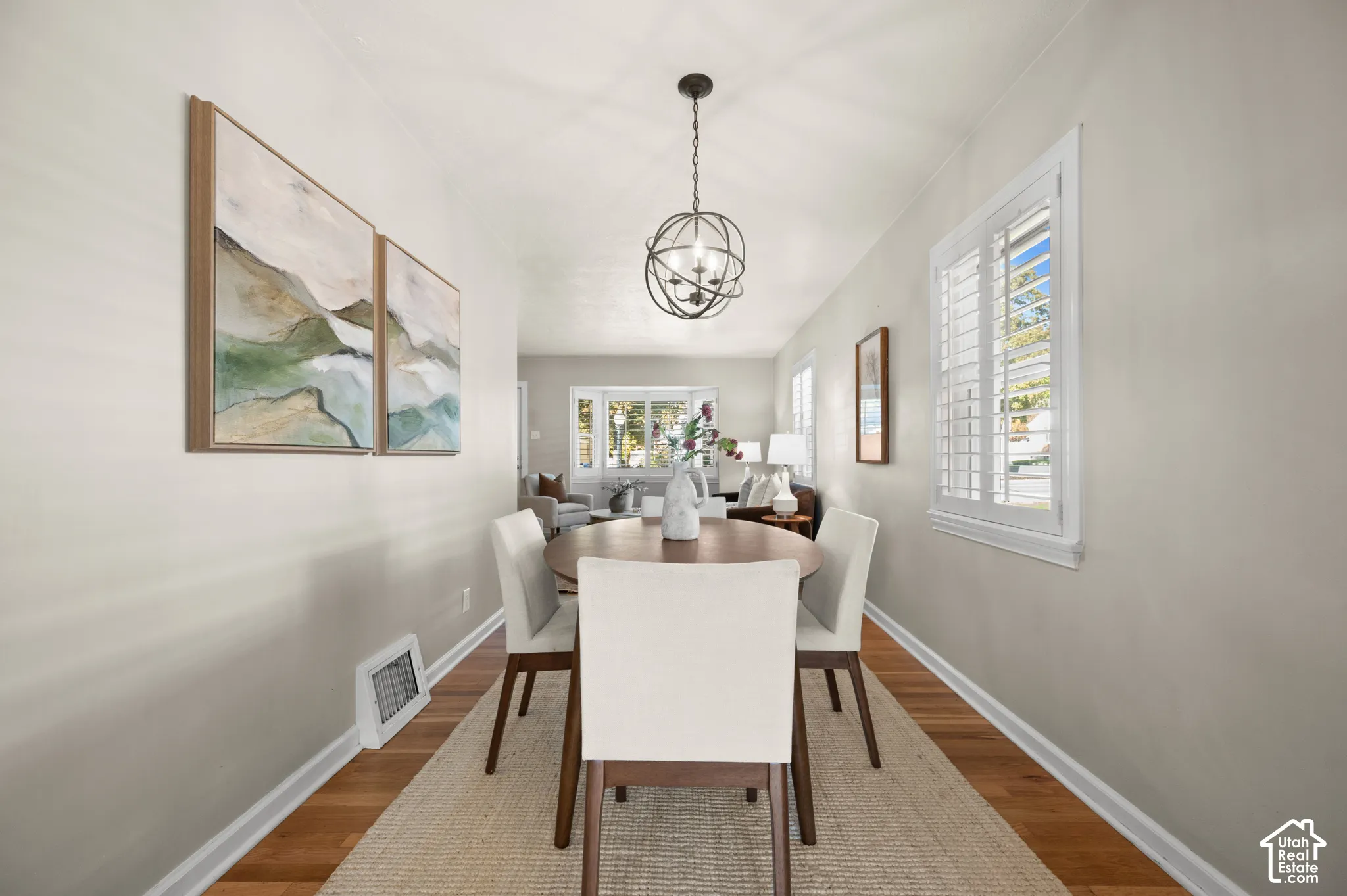 Interior area featuring wood-finish flooring, white plantation shutters, and a decorative orb pendant light fixture