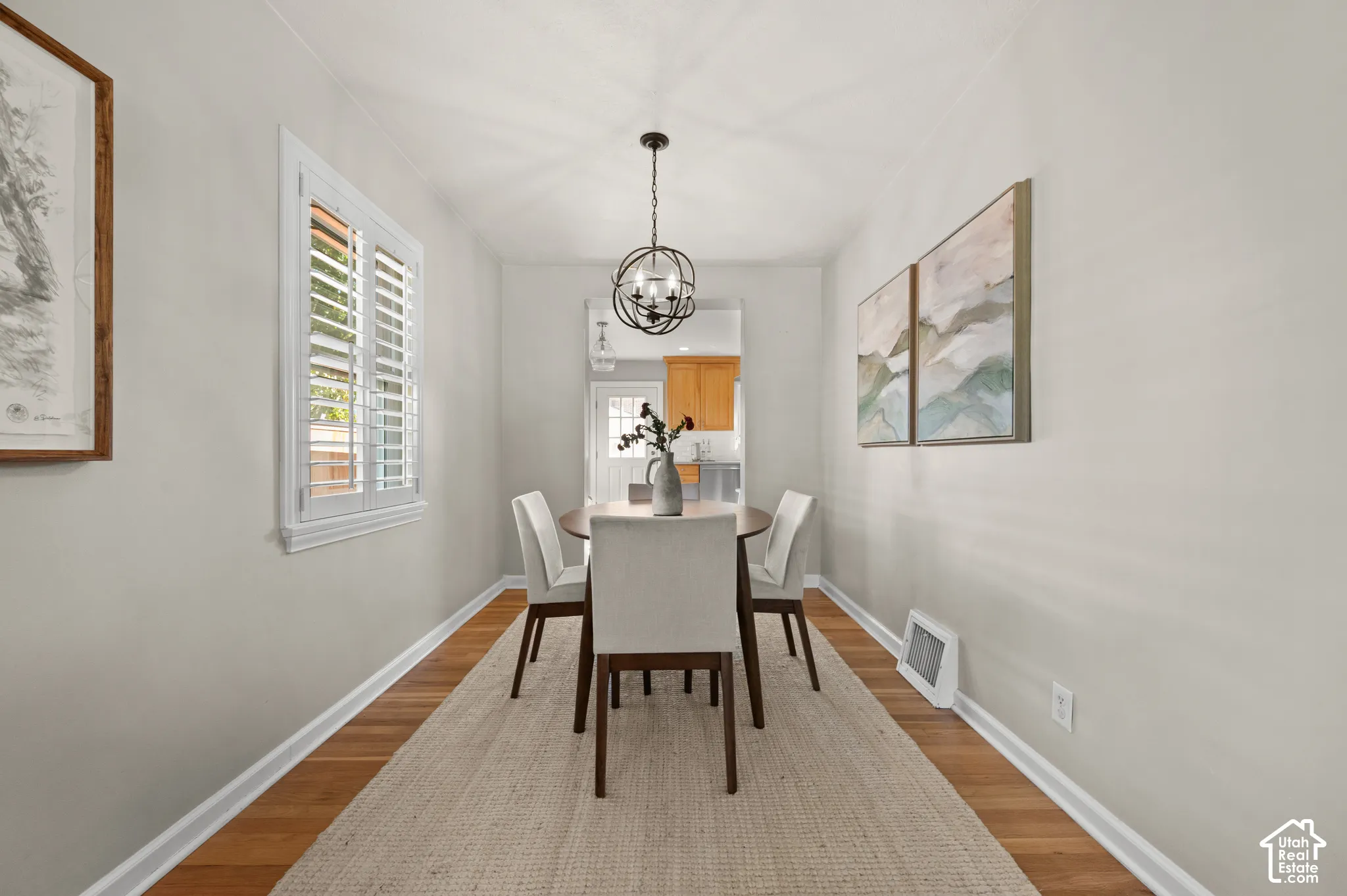 Dining area featuring wood-finish flooring, a spherical chandelier, and white plantation shutters