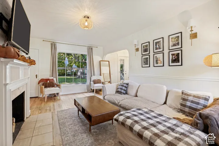 Living area featuring a traditional fireplace with a white mantel, an overhead decorative light fixture, and two wall sconces