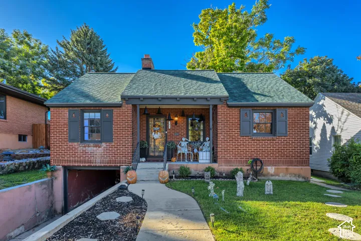 Brick exterior with dark shutters, covered front porch, and a green shingle roof