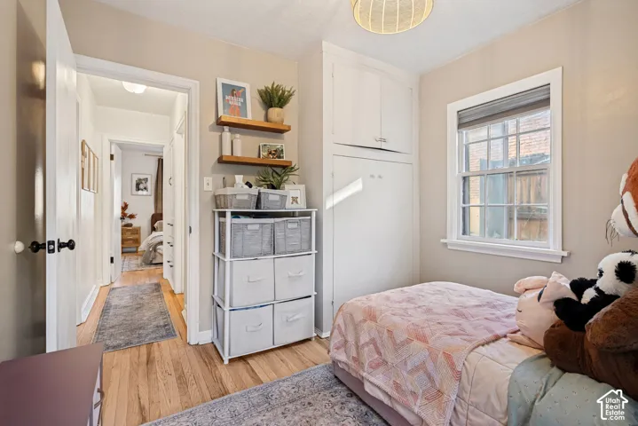 Wood-finish flooring throughout, built-in cabinetry, double-hung window, flush-mount ceiling light fixture, and wall-mounted shelving