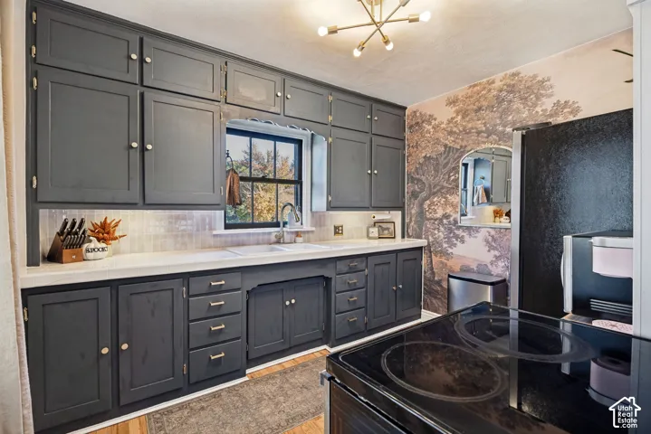 Dark-toned cabinetry, light-toned countertops, a tile backsplash, and a contemporary ceiling fixture
