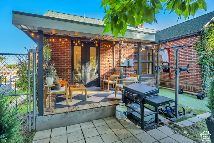 Brick exterior featuring a covered patio, checkerboard-patterned outdoor flooring, and French doors