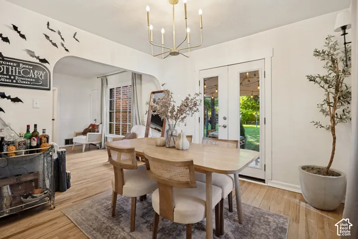 Hardwood flooring, arched doorway, French doors, recessed windows, and a brass chandelier