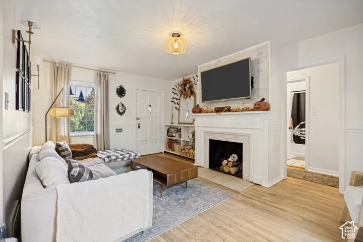 Hardwood-style flooring, white wainscoting, recessed lighting, fireplace with mantel, and a built-in shelving unit