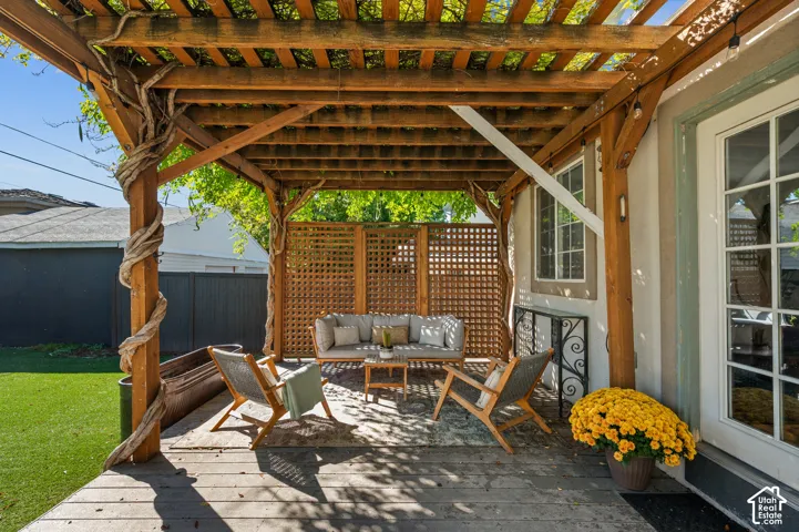Wood pergola with climbing vines, wood deck, latticework privacy screen, stucco exterior, and French patio door