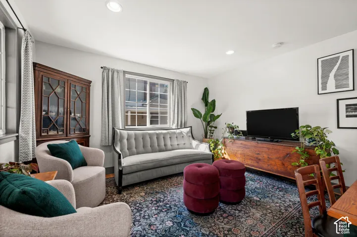 Recessed lighting illuminates a bright living area with light-toned walls and wood-finish flooring