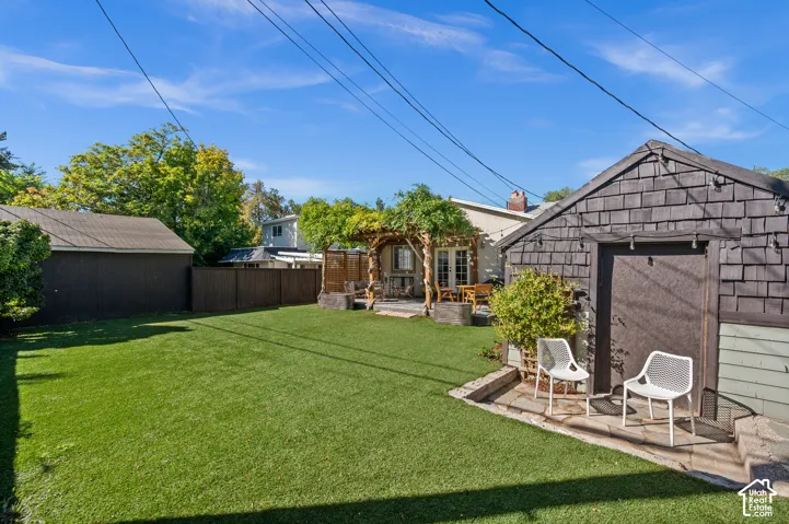 Expansive artificial turf lawn, privacy fencing, wood-clad storage shed, and a detached structure with shingle siding and a covered entry