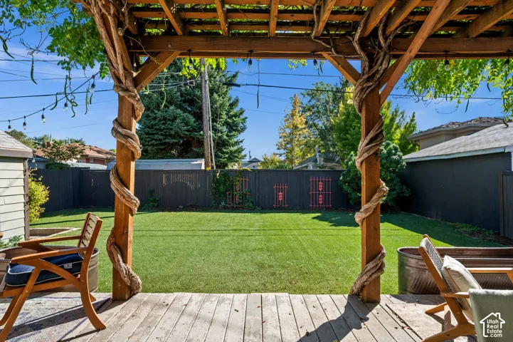 Wood deck featuring a pergola with natural wood posts and overhead string lighting